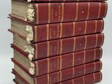 six livres rouges empilés les uns sur les autres sur une surface blanche