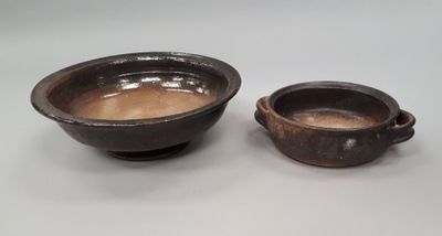 pair of brown pottery bowls with handles on a white surface