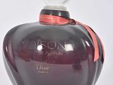 une image représentant un flacon de parfum posé sur une surface blanche