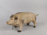 un petit cochon en peluche posé sur une surface blanche
