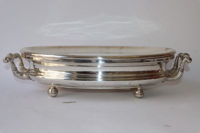 un plat en argent muni de poignées, sur un fond blanc