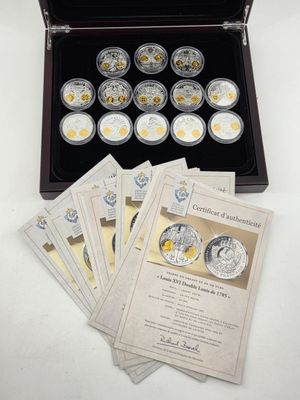 several silver coins are in a wooden case on a white table
