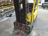 a yellow forklift in a warehouse with shelves of pallets