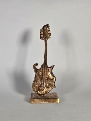 figurine de guitare en laiton posée sur un socle en marbre, sur fond blanc