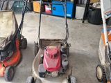 Trois tondeuses à gazon sont alignées dans un garage