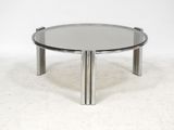 a round glass coffee table with chrome legs and a glass top