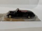 a black toy car and a red toy car on a white surface