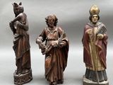 three wooden figurines of men with hats and robes