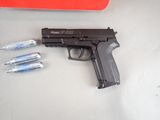 a gun that is sitting on a table next to some screws