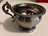 a silver bowl on a table with a spoon in it