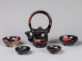 three black and red bowls and a teapot on a table