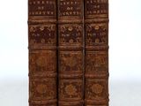 three old books are stacked on top of each other on a white surface