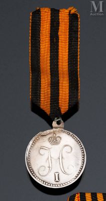 une vieille médaille entourée d'un ruban et une médaille surmontée d'une couronne