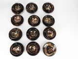 six black and gold buttons are arranged on a white surface