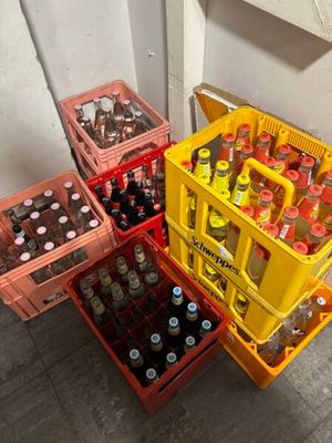 Plusieurs caisses de bière sont empilées les unes à côté des autres sur le sol.