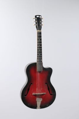 a red and black guitar hanging from a string on a white wall