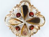 an image of a gold and garnet stone broochle on a white background