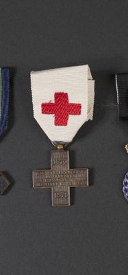 three medals and a cross are on a black surface