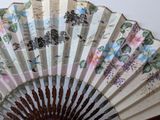 a close up of a fan with flowers painted on it