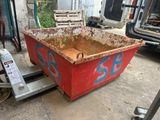 une benne rouge couverte de graffitis, garée dans un garage