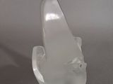 an image of a clear glass sculpture of a fish on a gray surface