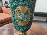 a green vase sitting on top of a wooden table