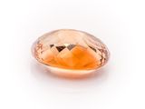 a close up of a faceted orange sapphire stone on a white surface