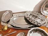 a lot of silver dishes and spoons on a table