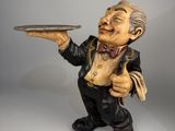 figurine représentant un vieil homme tenant un plateau, le sourire aux lèvres