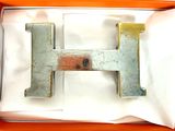 une lettre « h » en métal dans une boîte posée sur une table