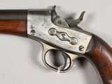 a close up of a gun with a wooden handle on a white surface