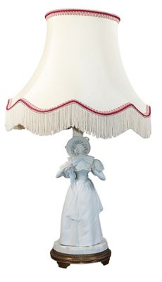 une image représentant une lampe avec un abat-jour blanc et une figurine de femme posée dessus