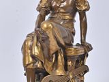 bronze statue of a woman sitting on a stool with a guitar