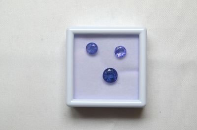 trois saphirs bleus dans un cadre blanc, sur un fond blanc