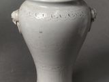 a white vase sitting on a table with a gray background