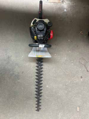un gros plan d'un coupe-haie posé à même le sol dans un garage