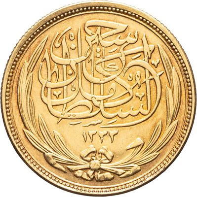 a close up of a gold coin with arabic writing on it