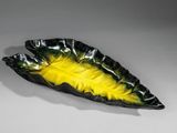 plat jaune et noir en forme de feuille sur un fond blanc