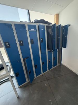 Plusieurs casiers bleus sont alignés le long d'un mur dans une pièce