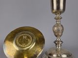 assiette en argent et tasse en argent posées sur un support, sur fond gris