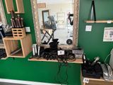 un miroir accroché au mur au-dessus d'une étagère où sont rangés des sèche-cheveux et d'autres objets