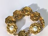 une image représentant un bracelet en or orné de perles sur un fond blanc
