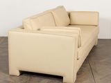 beige leather sofa in a room with wood flooring and a white wall