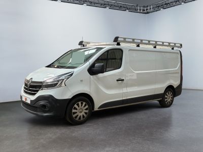La camionnette blanche est garée dans une grande pièce, avec une échelle sur le toit.