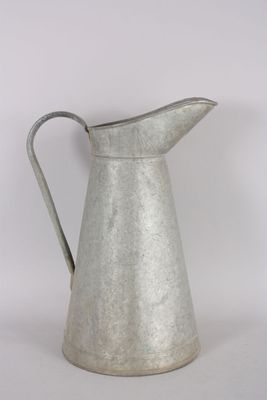 an old metal pitcher with a handle sitting on a table