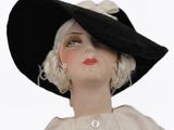 a doll with a black hat and a white dress