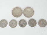 six different coins are arranged in a row on a white surface