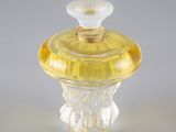 flacon de parfum en verre jaune, muni d'un bouchon doré et orné d'une fleur sur le dessus