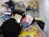 a white bag filled with various items on a bed