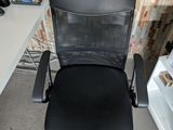 a black office chair sitting in front of a computer desk